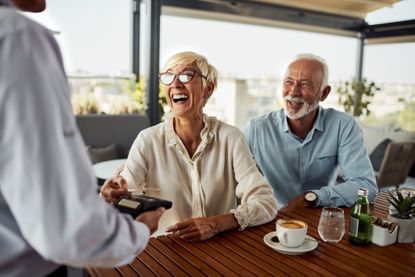 A mature couple at a cafe using credit card perks.