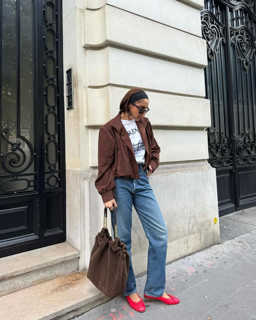 Influencer @erinoffduty wears straight leg jeans with a graphic tee, suede jacket, and red ballet flats.