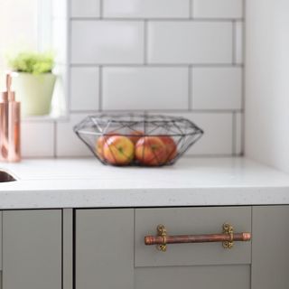 grey cabinet and white marble top with fruits in container