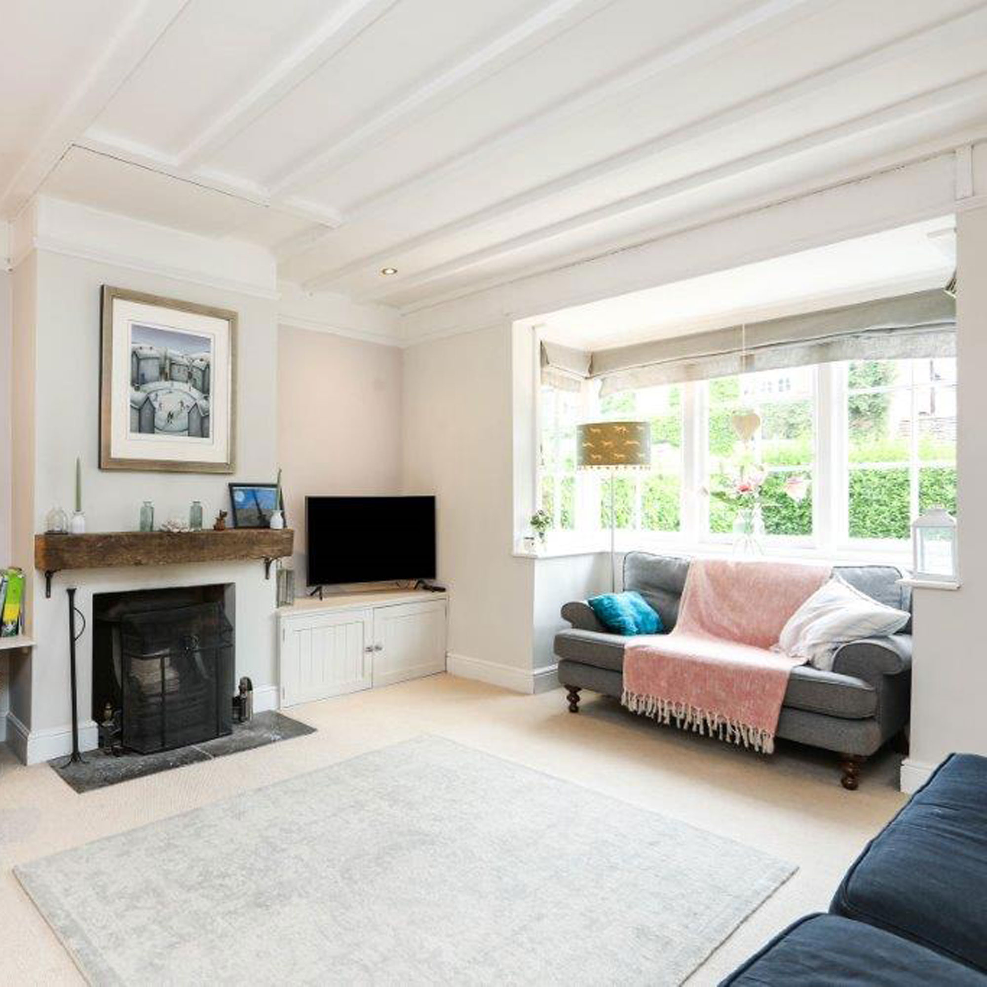 living room with open fire and bay window with small grey sofa