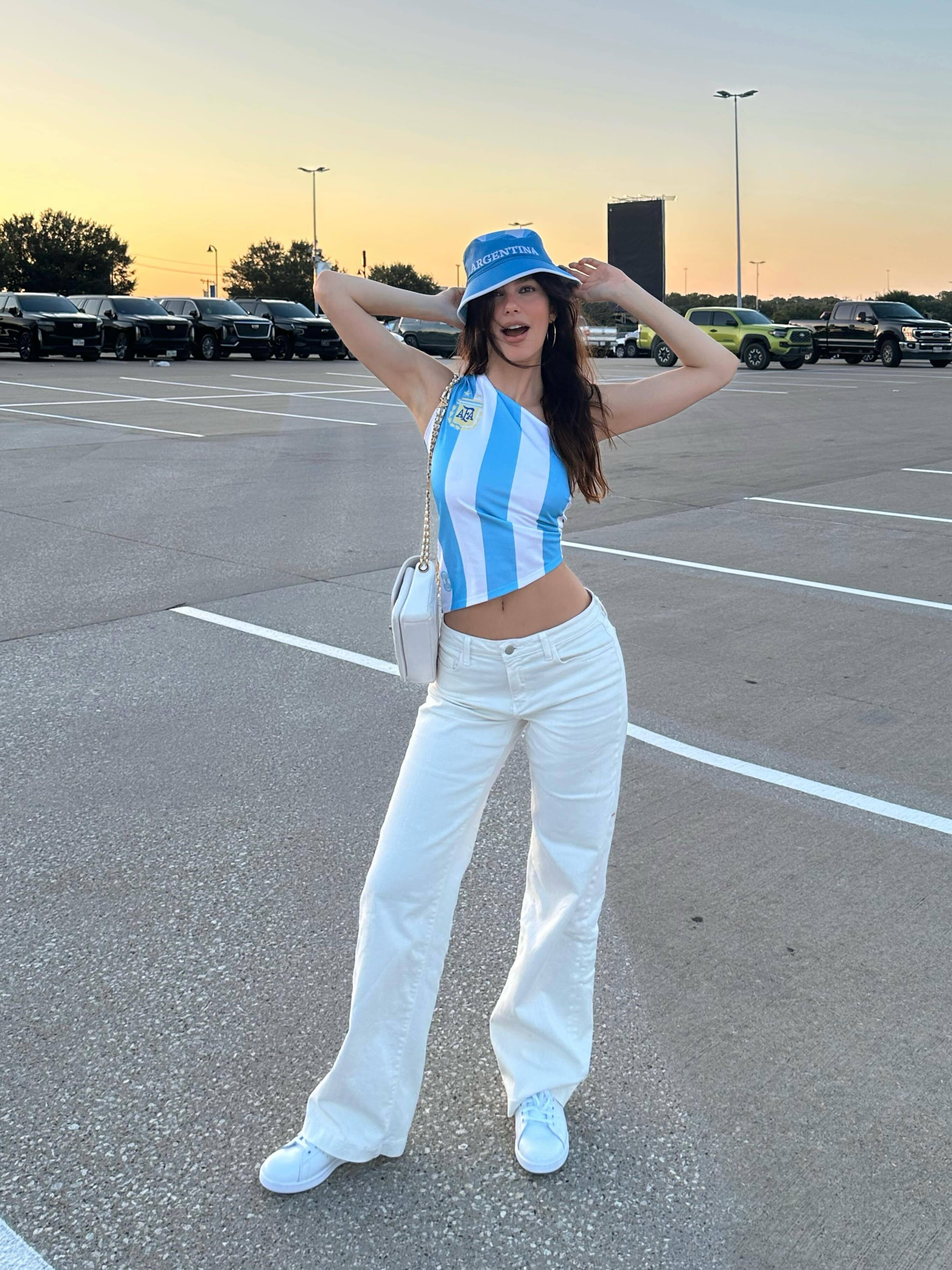 Camila Morrone wears the white sneaker summer trend with matching jeans and Team Argentina gear