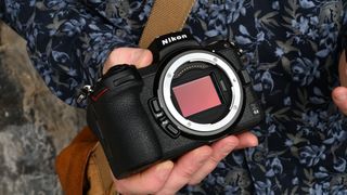 Nikon Z7 II camera held in a hand in front of a patterned shirt