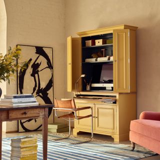 workstation contained in yellow dresser in living room with wooden table in foreground