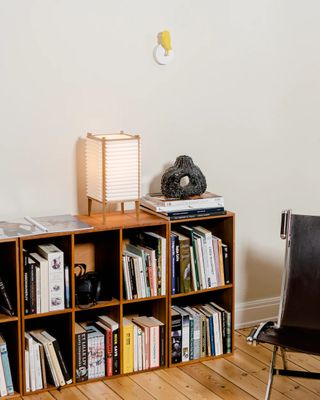 Modern living room bookshelf with a yellow Birdie product hanging on the white wall