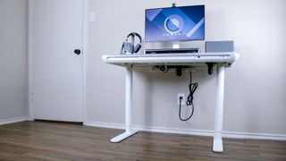 The LiftSync Clear Plus standing desk against a white wall