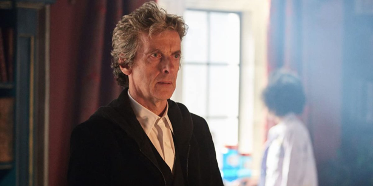 Peter Capaldi stands with a stern expression on his face in Doctor Who.