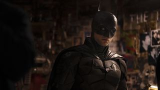Robert Pattinson som Batman, stående i et rom fullt av bilder, skjermbilde fra «The Batman»