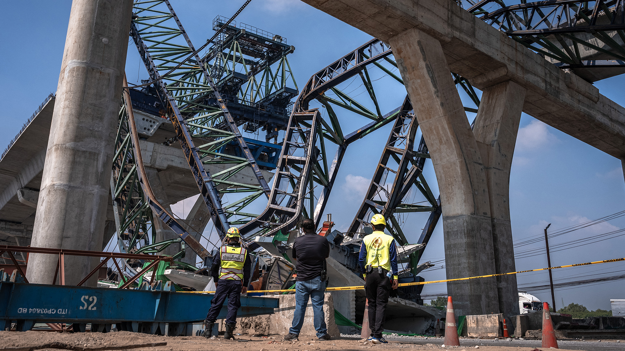 Recovery workers stand beside a highway construction site after a fatal crane collapse in Samut Sakhon province, Thailand