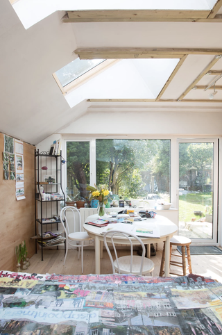 Garage conversion ideas: a garage transformed into an art studio, with white walls and a dining table, and artwork on the table