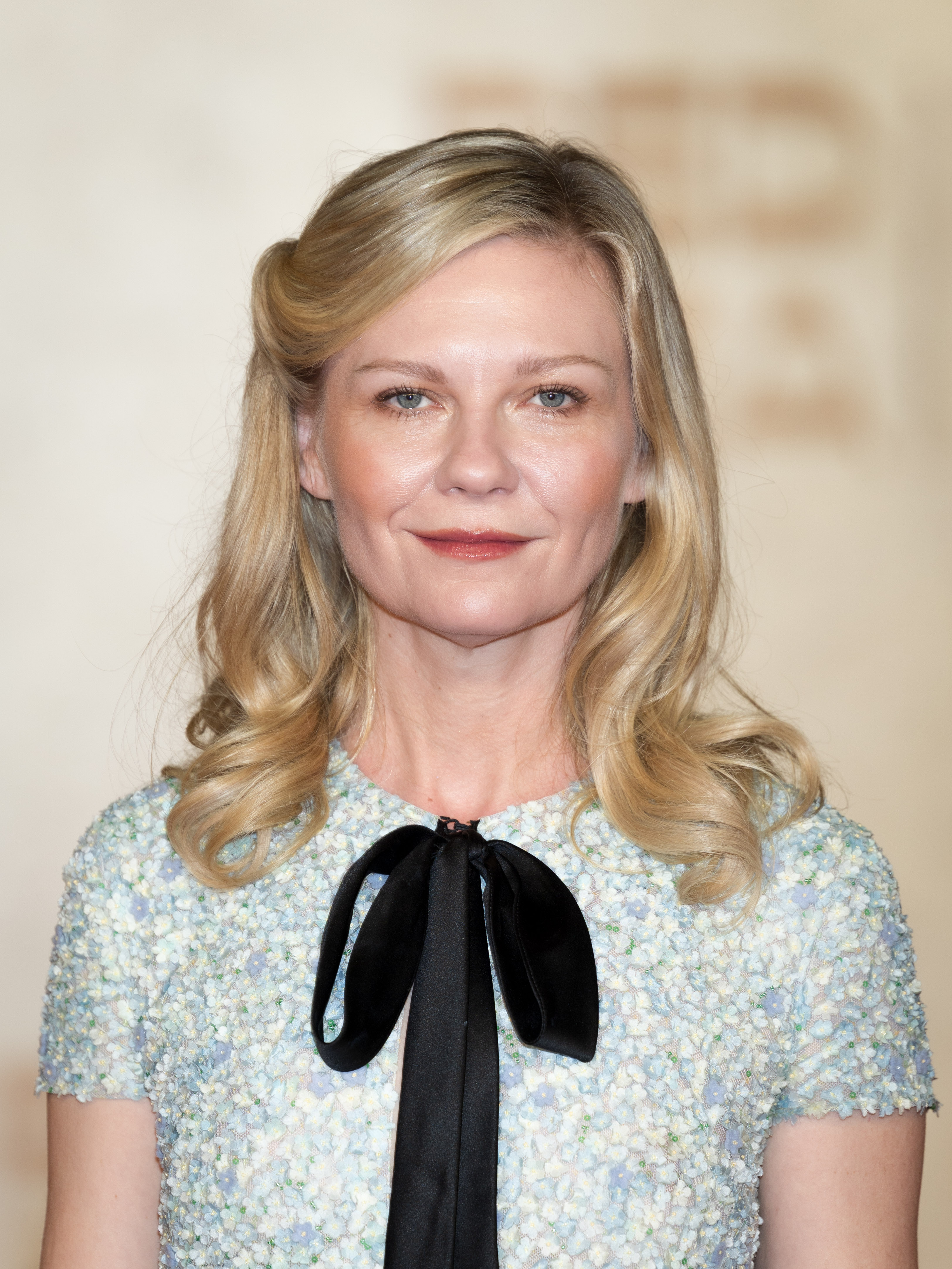 a white woman with blonde hair wearing a blue dress with a black bow