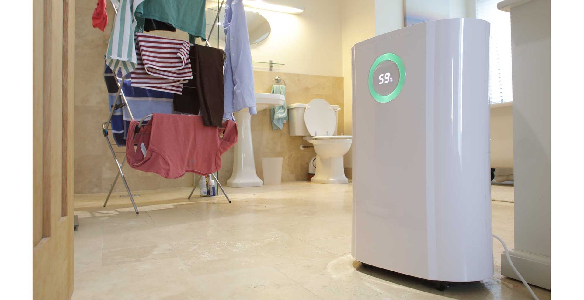 Dehumidifier in the doorway of a bathroom drying laundry to show how much moisture they collect