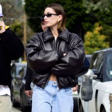 Hailey Bieber wears a black leather jacket with jeans