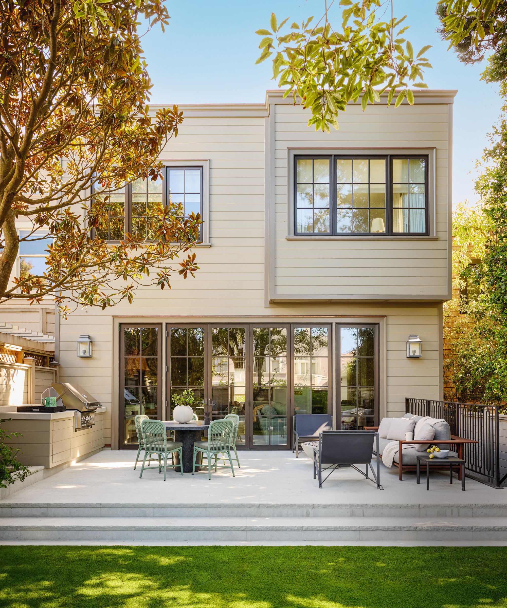 a remodeled 1905 san francisco home with beige paneled facade, large patio with french doors and grass area