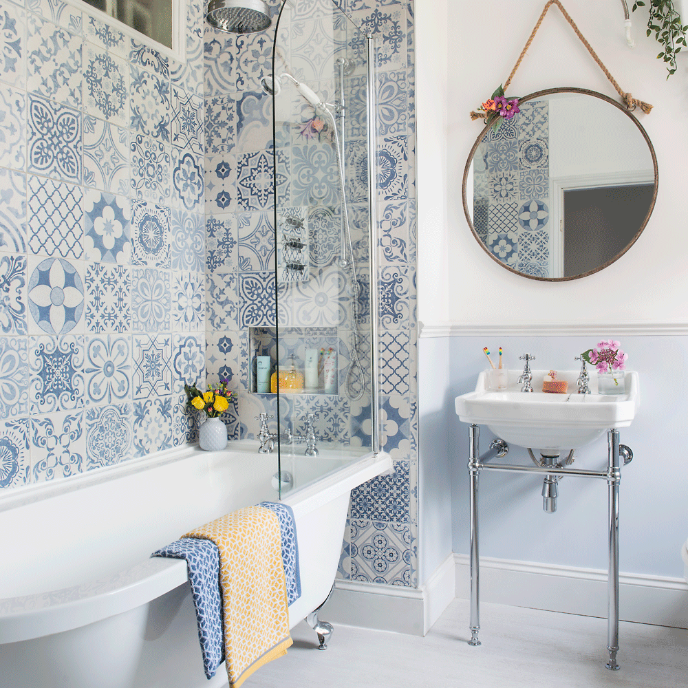 bathroom with blue designed tiles wall bathtub wash basin and mirror on wall