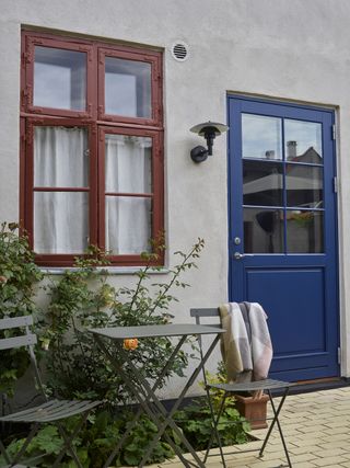 A white house with a bright dark blue door and brown window