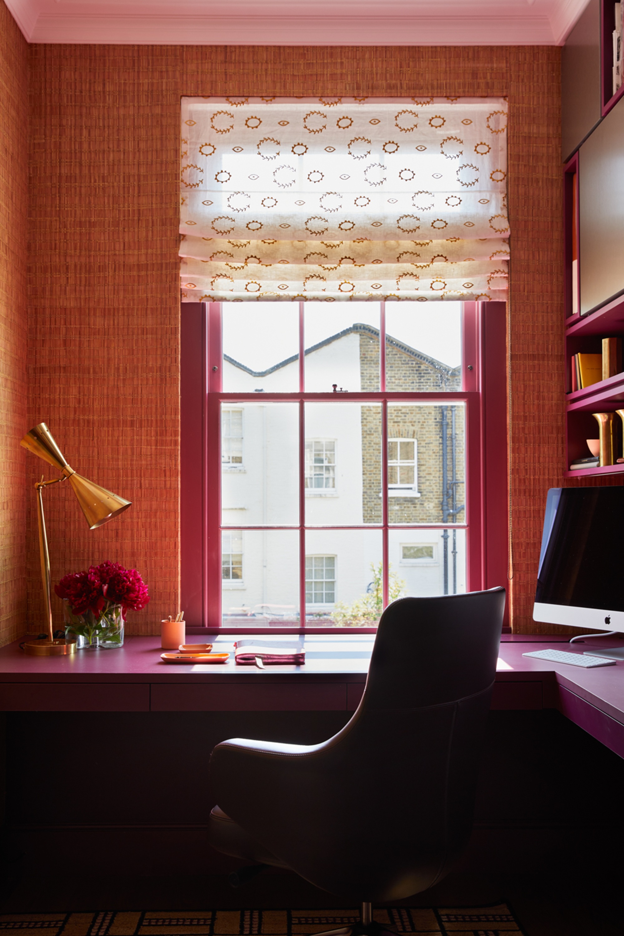 a home office with pink woodwork and orange wallpaper