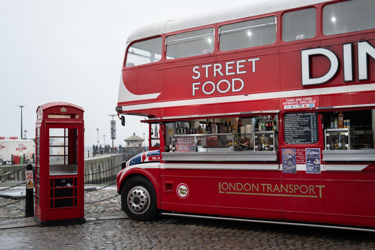 A red London phone box next to a red London bus converted into a restaurant