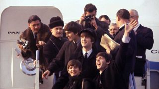 A pictures of The Beatles and their entourage leaving a plane in Beatles '64