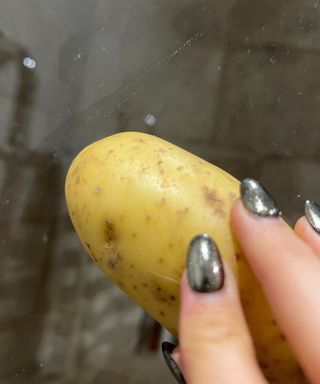 Wiping a shower screen with half a potato