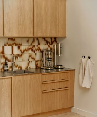 A wooden kitchen with wooden hardware and patterned tile backsplash