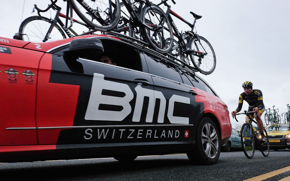 A rider competing in stage three of the Tour de Yorkshire cycle rides behind a BMC team car