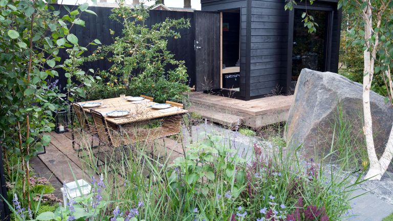 garden with timber decking, wooden garden sauna and black painted fences