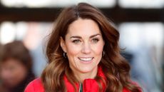 Kate Middleton, wearing a red jacket and green jumper, smiles during a visit to Peterley Manor Farm on December 4, 2019