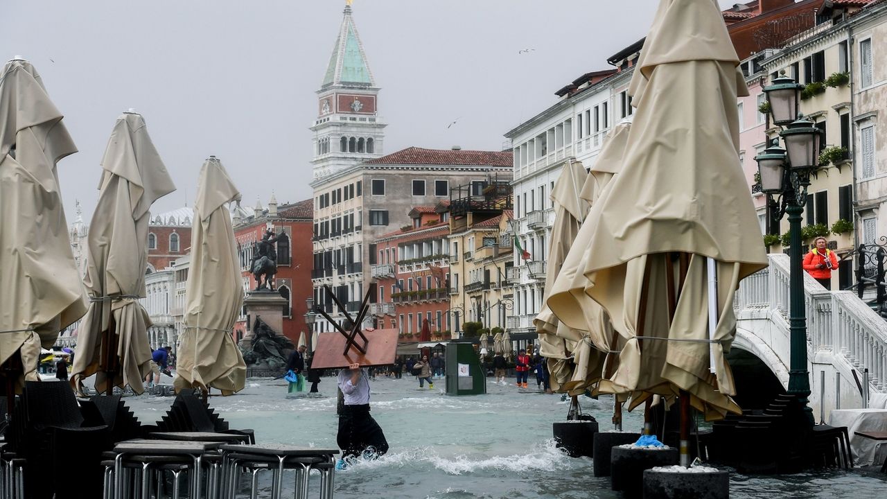 A man carries a table in the flooded Riva degli Schiavoni during a high-water (Acqua Alta) alert in Venice on October 29, 2018. - The flooding, caused by a convergence of high tides and a str