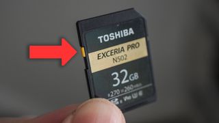 An arrow pointing to the write protect tab on an SD memory card