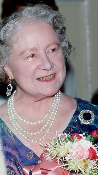 Queen Elizabeth, the Queen Mother, wearing diamond and sapphire fringe earrings, attends a Ben Travers farce on his 93rd birthday in November 1986.