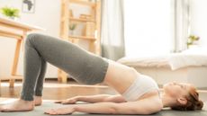 A woman lying on the floor performing the glute bridge