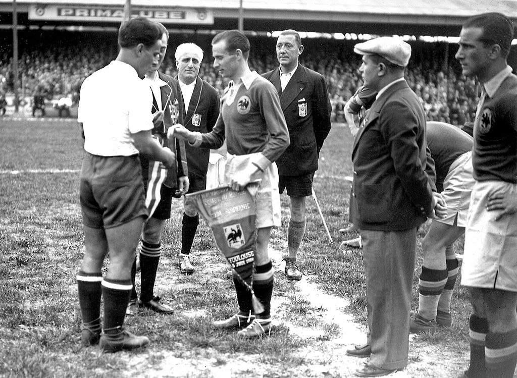 Cuban national soccer team captain Manuel Chorens (L) exchanges pennants with his Romanian counterpart Gheorghe Rasinaru before the start of the World Cup preliminary round soccer match between the two teams 05 June 1938 in Toulouse. The match ended in a 3-3 draw. Four days later, Cuba won in a rematch 2-1. AFP PHOTO (Photo credit should read STAFF/AFP via Getty Images)