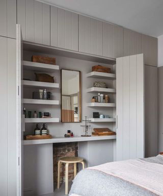 A master bedroom with grey wardrobe and dressing room niche with chair