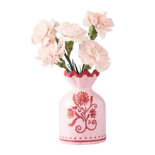 A pink scalloped vase with red illustrations and pink carnations
