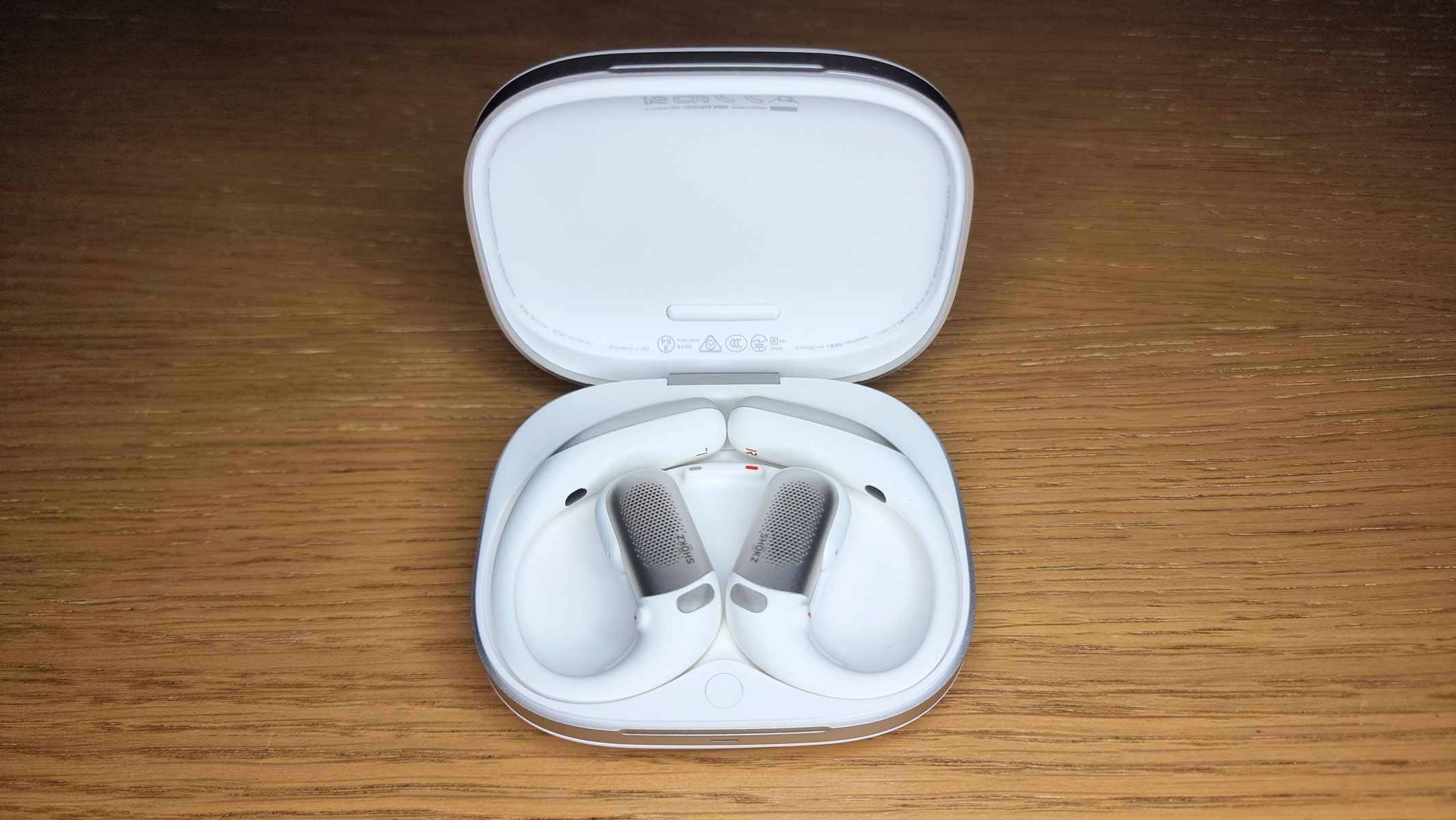 An open charging case with the Shokz OpenFit Pro earbuds in it