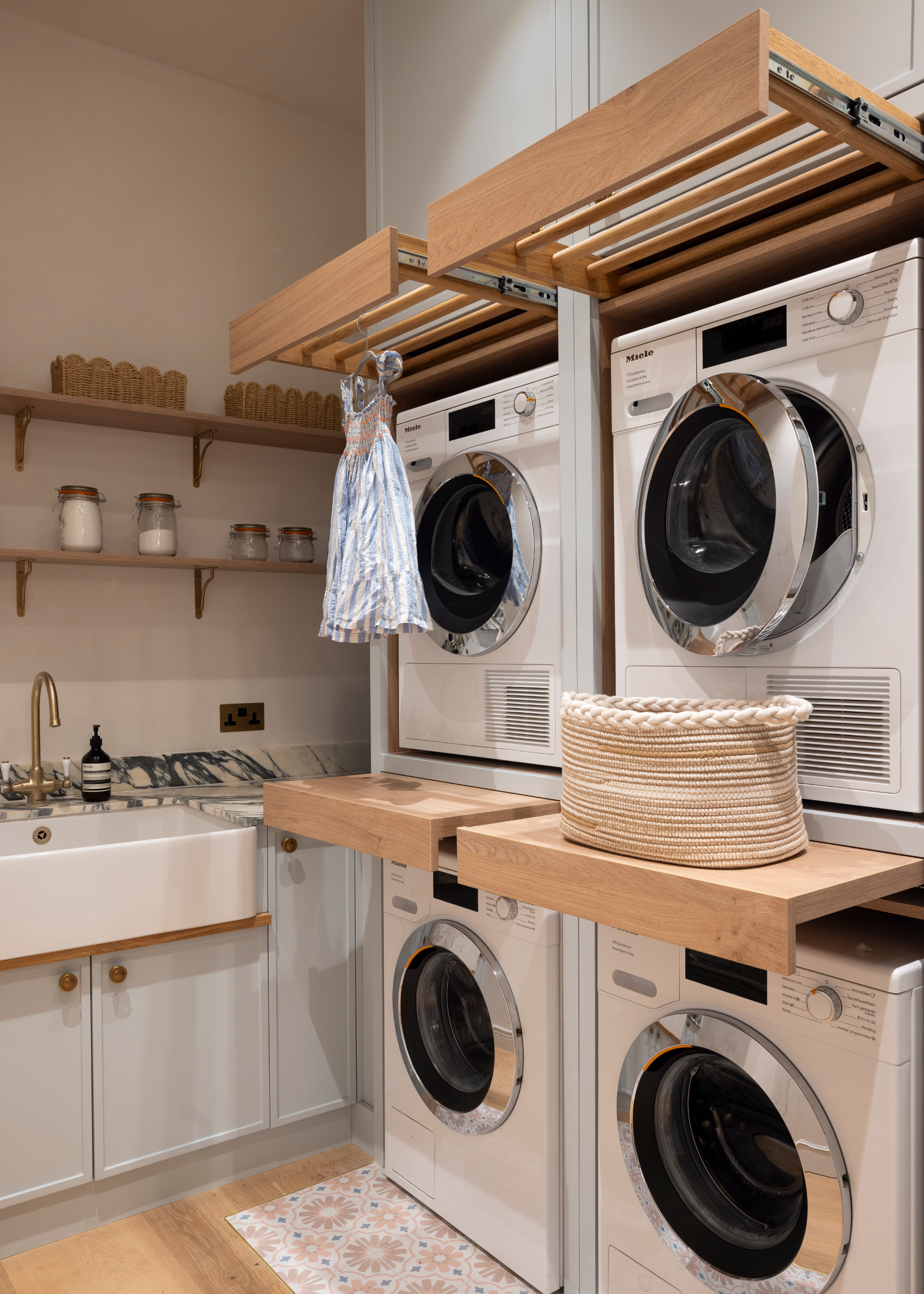 a laundry room with two washers and two dryers and custom clothes racks concealed above each one