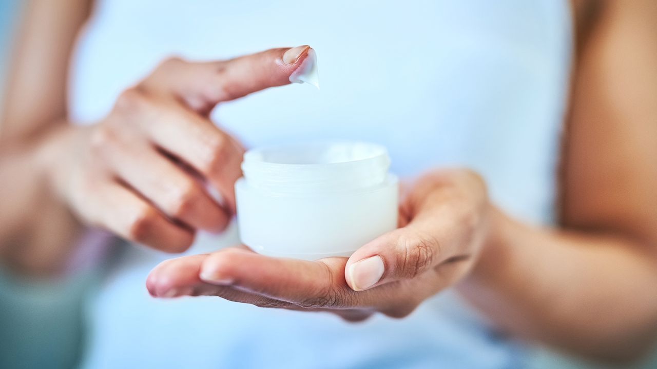 close up of woman&#039;s hands holding jar of face cream