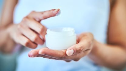 close up of woman's hands holding jar of face cream