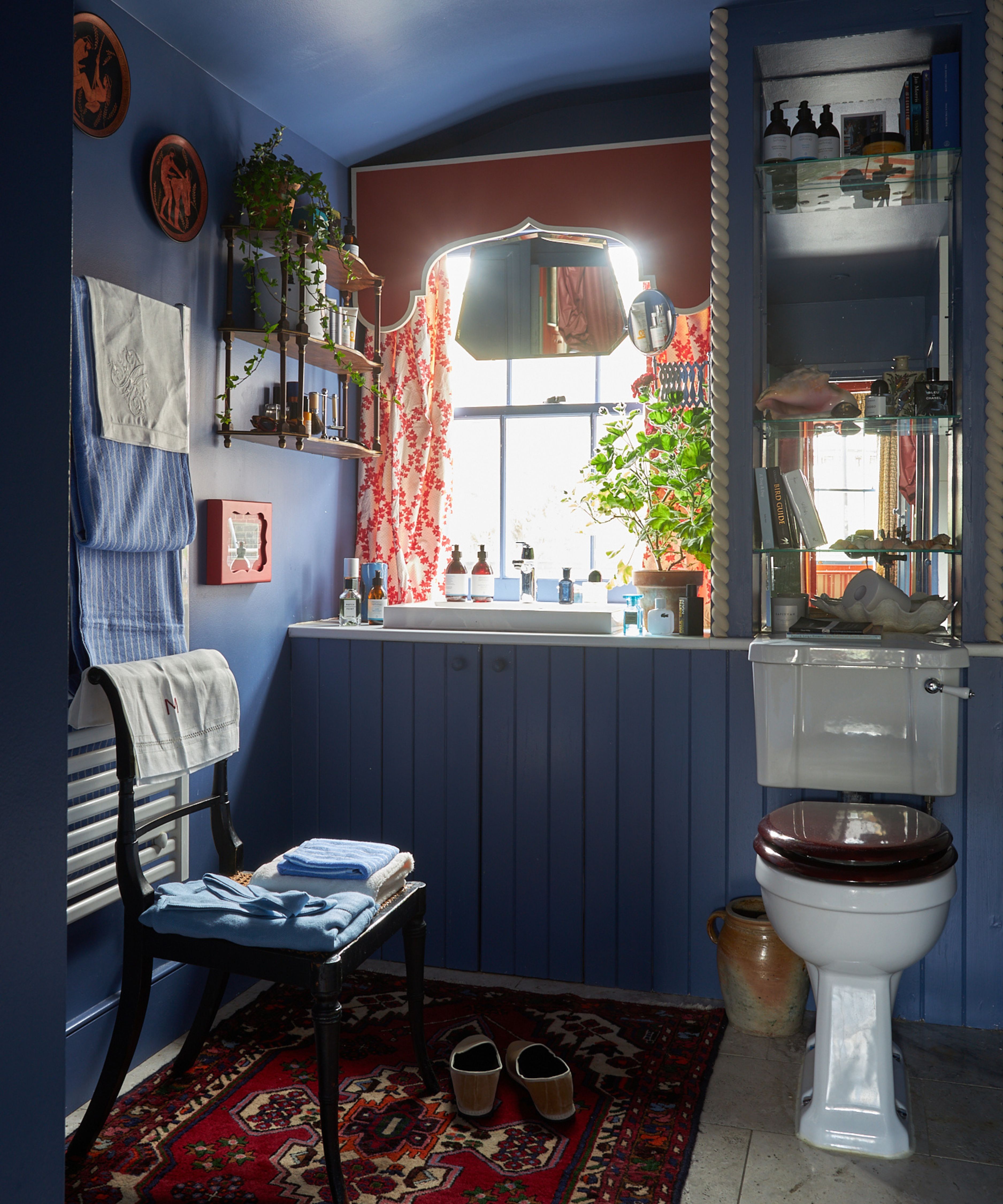 small bathroom with vintage styling painted in a dark blue farrow &amp;amp; ball paint with a red pelmet and curtains at the window