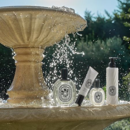 Diptyque summer collection products sitting on water fountain in garden