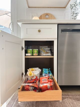 An open kitchen cabinet with the bottom drawer pulled out.