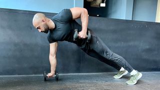 a photo of trainer Ali Malik performing a dumbbell renegade row