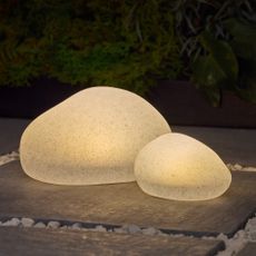 Next Natural Pebble Outdoor Solar Lights on a patio glowing in the dark