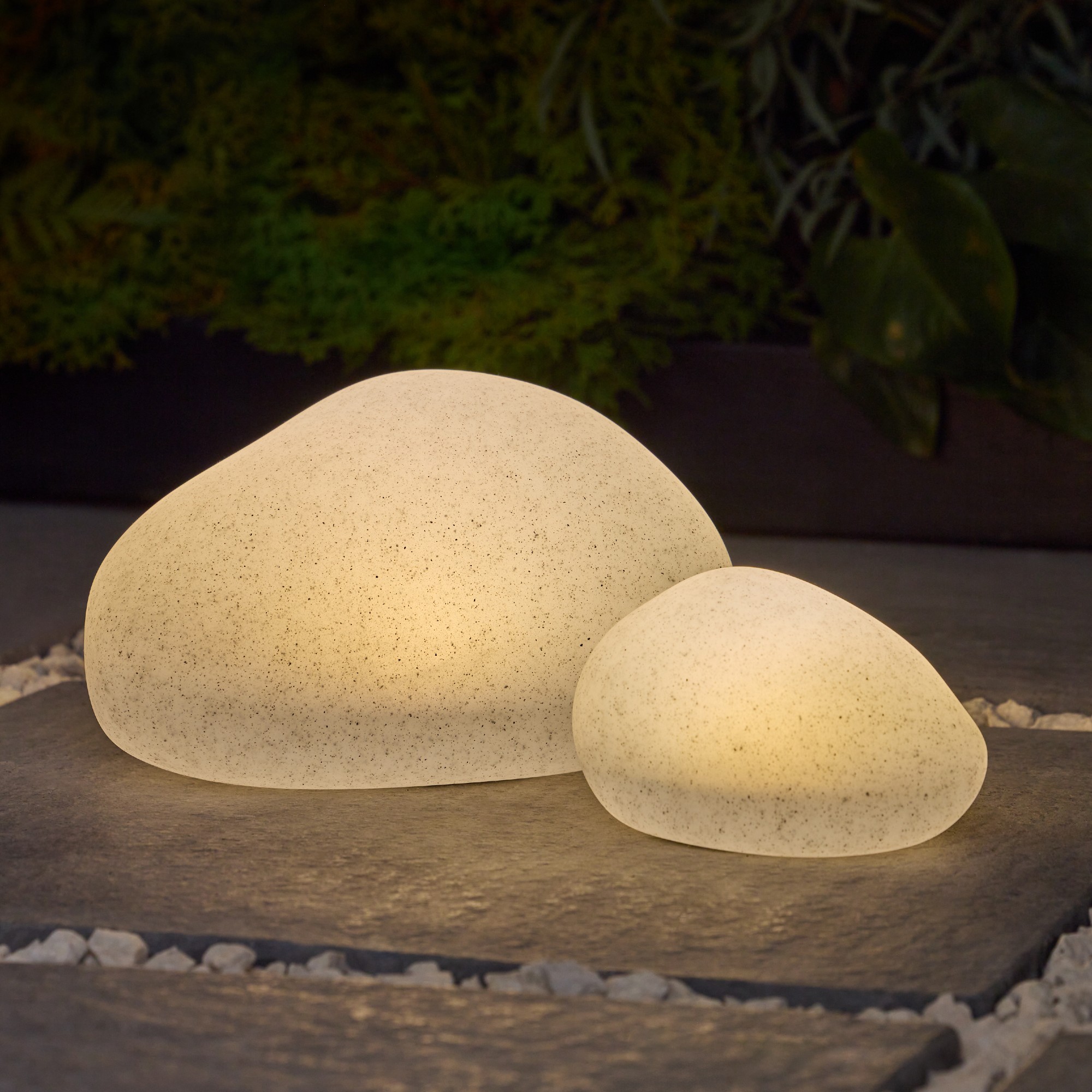 Next Natural Pebble Outdoor Solar Lights on a patio glowing in the dark