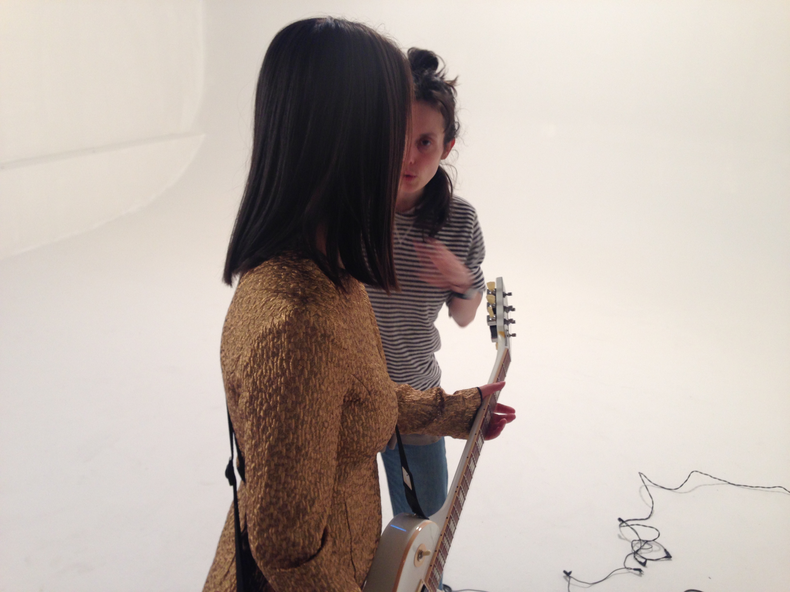 behind the scenes photo from the set of the your best american girl music video featuring mitski talking to director zia anger against a white background
