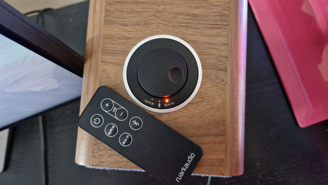 Ruark MR1 Mk2 Bluetooth Speakers review image showing scroll wheel atop the right speaker with the remote control sitting next to it