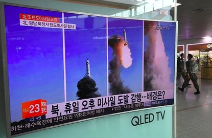 A television screen shows footage of a North Korean missile launch.