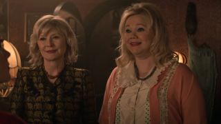 Beth Broderick and Caroline Rhea stand together smiling in Chilling Adventures of Sabrina.