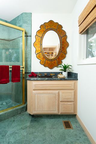 gold antique mirror in bathroom with green tiling and white walls