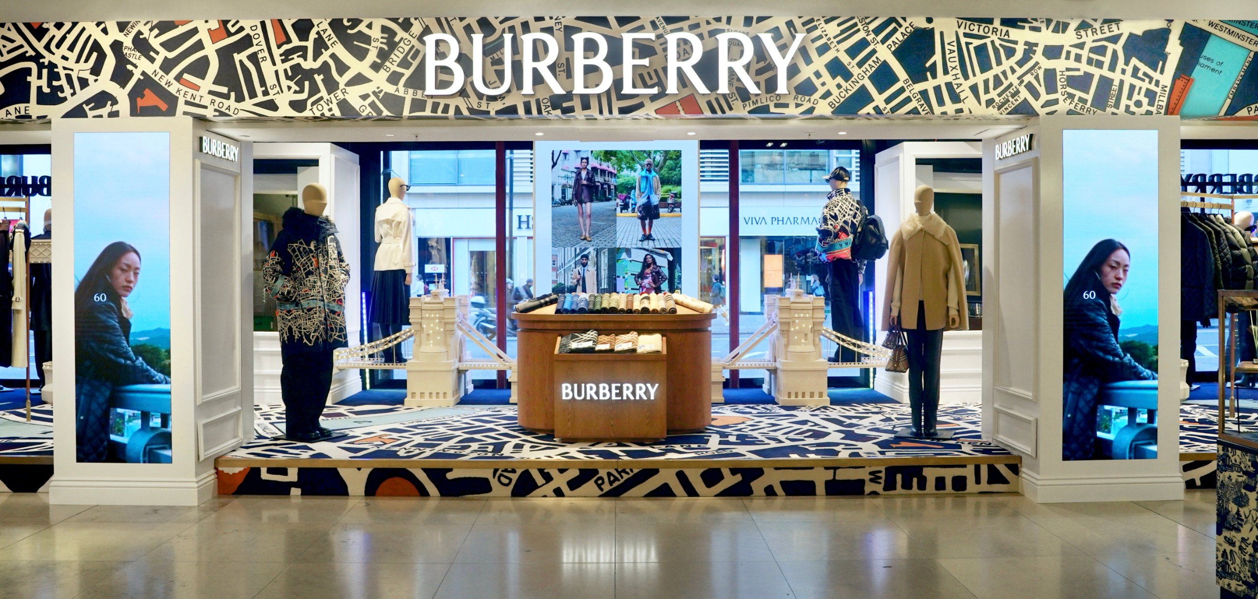 A pop-up space inside Harrods selling Burberry products. It's decorated with a London map-design wallpaper and carpet